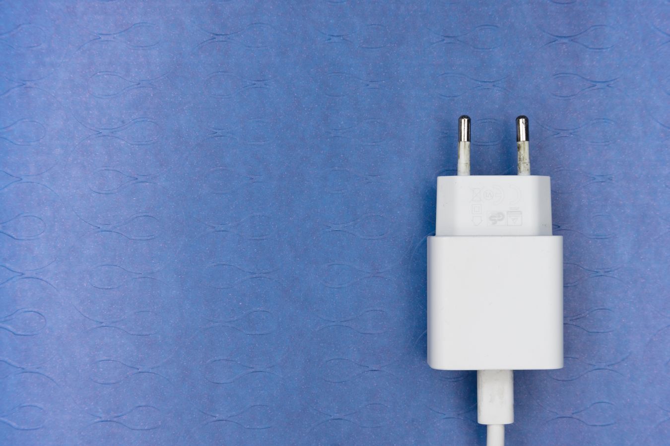 藍色背景上的歐規雙圓腳電源適配器，用於說明 CE 文件查核。