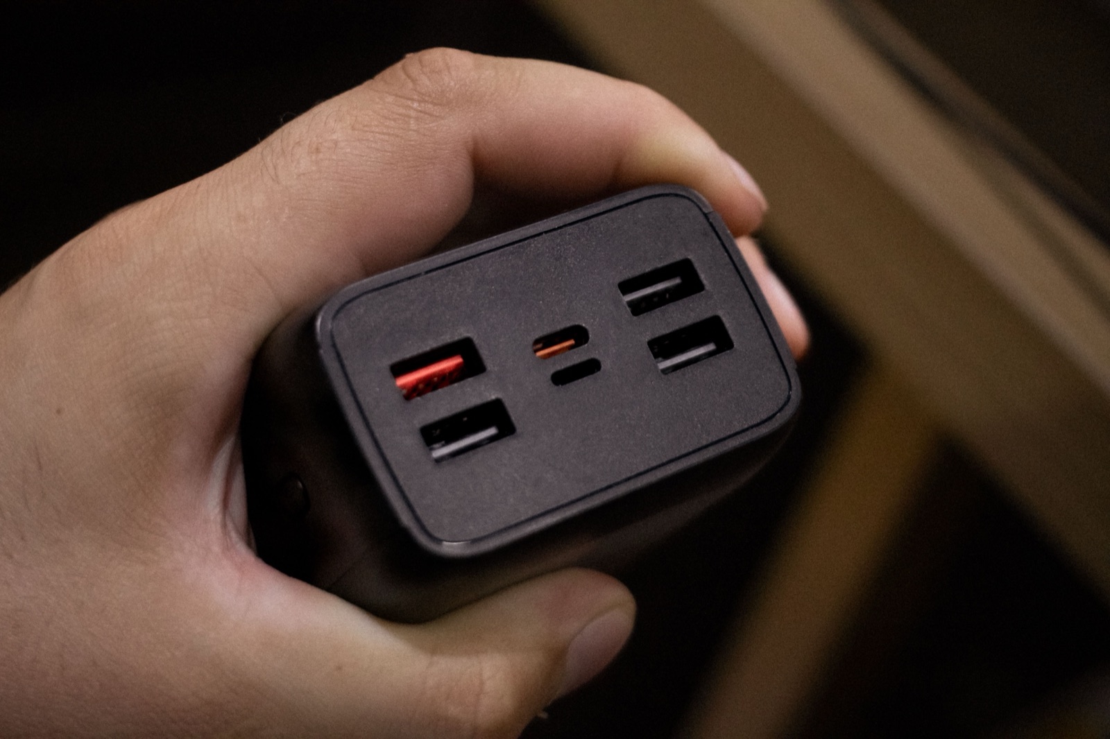 Hand holding a multi-port power adapter used as an editorial illustration for UL file verification.